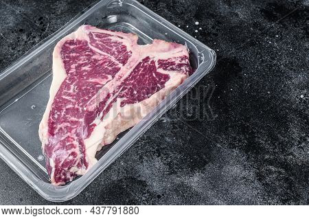 T-bon Raw Beef Steak In Vacuum Packaging. Black Background. Top View. Copy Space