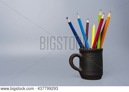 Colored Funny Pencils In A Clay Cup On A Gray Background, Colored Pencils In A Clay Glass. Tools For
