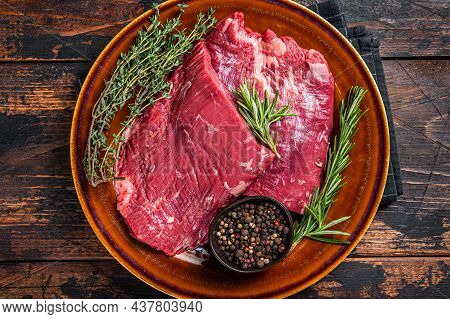 Two Flap Or Flank Raw Beef Steaks On A Rustic Plate With Herbs. Dark Wooden Background. Top View