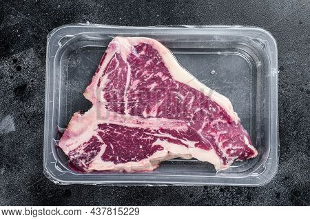 T-bon Raw Beef Steak In Vacuum Packaging. Black Background. Top View