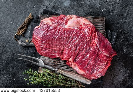 Uncooked Raw Flank Or Flap Beef Steak On Butcher Board. Black Background. Top View