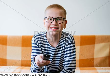 A Teenage Boy Watches Tv, Using Remote Control To Change Channels. Young Man Is Unhappy With What He