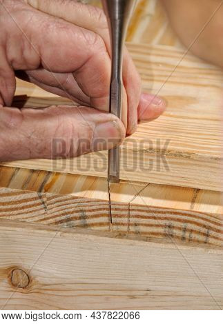Craftsman cutting a dovetail joint with a chisel