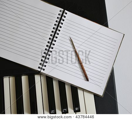 Notebook And Pen On Synthesizer Keys