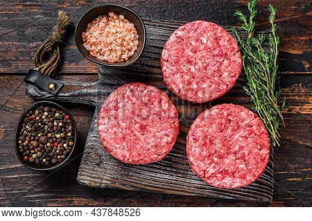 Raw Steak Burgers Patties With Ground Beef And Thyme On A Wooden Cutting Board. Dark Wooden Backgrou