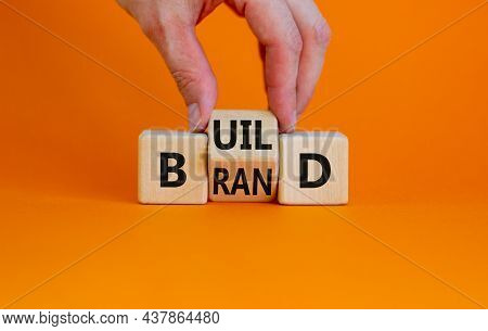Build Your Brand Symbol. Businessman Turns Wooden Cubes And Changes The Word 'build' To 'brand'. Bea