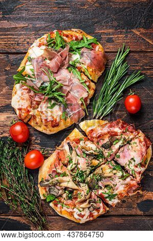 Sliced Pizza With Prosciutto Parma Ham, Arugula And Parmesan Cheese. Dark Wooden Background. Top Vie