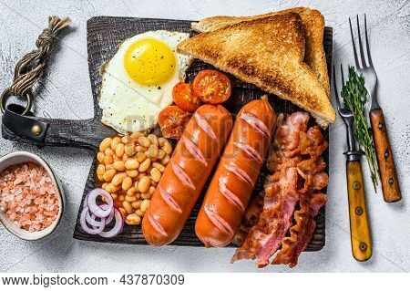Full Fry Up English Breakfastt With Fried Eggs, Sausages, Bacon, Beans And Toasts On A Wooden Cuttin