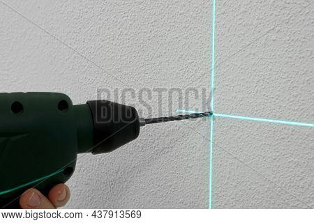 Using Cross Line Laser Level For Accurate Measurement And Drilling Hole In White Wall, Closeup