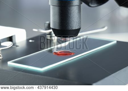 Glass Slide With Sample Of Red Liquid Under Microscope In Laboratory, Closeup