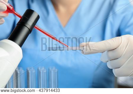 Scientist Dripping Sample Of Red Liquid Onto Microscope Slide In Laboratory, Closeup
