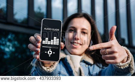 Audio Tour Online App On Digital Mobile Smartphone. Happy Young Student Woman Holding Phone Listenin