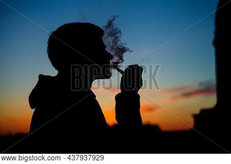 Silhouette Photo Of Unrecognizable Man With Smoking Pipe. Male Lights Up His Pipe And Blows Smoke. S