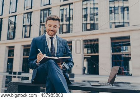 Professional Smiling Firm Worker In Formal Suit Writing Down Ideas With Pen In Note Book While Sitti