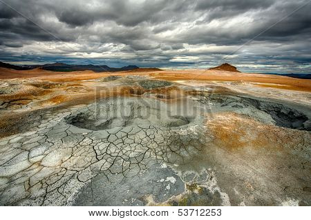 Mudpots in the geothermal area Hverir, Iceland. The area around the boiling mud is multicolored and cracked. HDR image