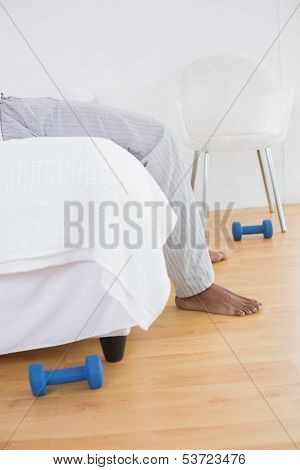 Side view low section of a young man in pajama lying in bed at a bright home