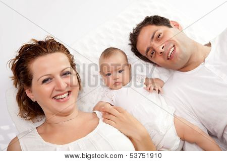 Happy Young Family Lying In Bed