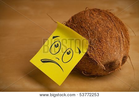 Drawn smiley face on a post-it note sticked on a coconut