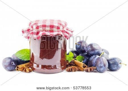 Jar with plum butter, plums and spices on white
