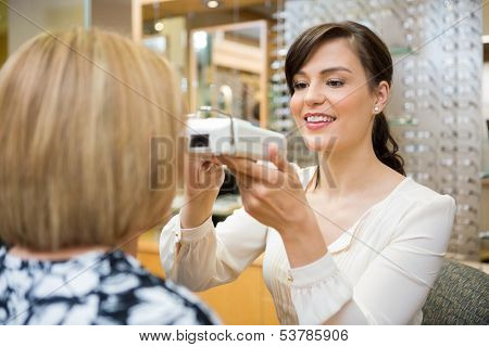 Young female optometrist measuring pupilary distance on senior customer