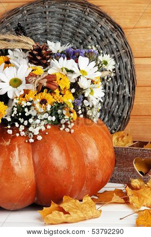 Beautiful autumn composition in pumpkin with decorative box on table on wooden background