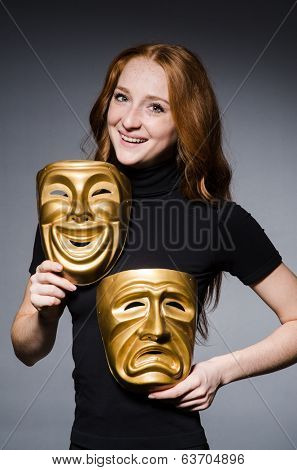 Redhead woman iwith masks in hypocrisy consept against grey background