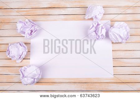 Sheet of white paper with crumpled  paper  and pencil on table close-up