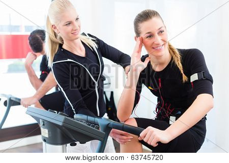 Female coach giving man and woman ems electro muscular stimulation exercise 