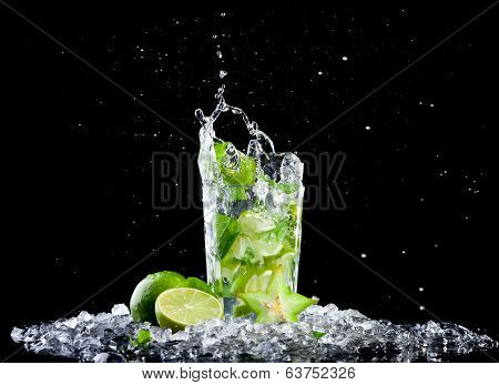 Studio shot of fresh mojito drink with ice cubes and splash on black background