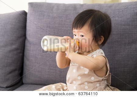 Adorable baby girl drinking milk from bottle 