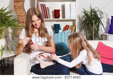 Mother And Little Daughter painting their nails and toes
