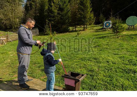 Father and son shoot arrows at a target.