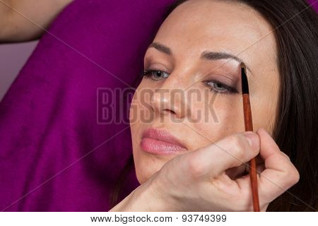 Makeup artist apply makeup on the face of the girl model.