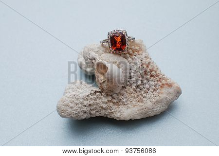 Orange citrine gold engagement ring on a shell and coral reef