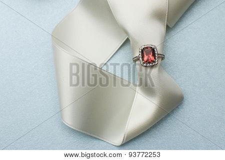 Orange citrine engagement ring on a white ribbon on a light blue background