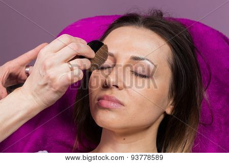 Work of make-up artist. Makeup artist apply makeup on the face of the girl model.