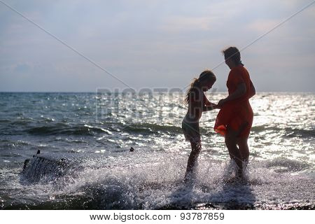 mother and daughter standing on the dock in the waves