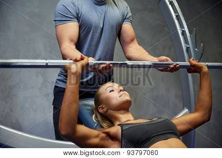 sport, fitness, teamwork, bodybuilding and people concept - young woman and personal trainer with barbell flexing muscles in gym