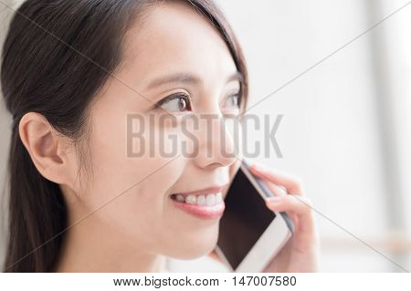 woamn talk on phone with white wall asian