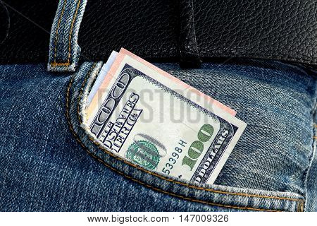 One hundred dollars bill sticking out of the blue jeans pocket