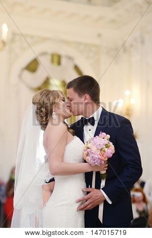 Beauty bride and handsome groom are registering the marriage. Wedding couple is marrying. Beautiful model girl in white dress and in lace veil. Man in suit. Female and male portrait. Cute lady and guy
