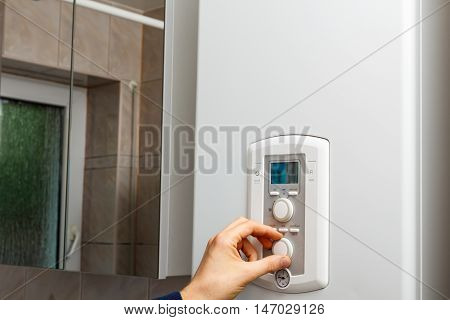 Men hand regulate temperature on DHW control panel.