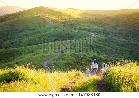 Mother and her daughters walking in hills in the evening