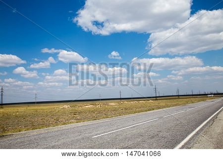 summer road trip under cloud sky with transmission towers on the background