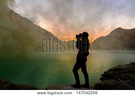 Silhouette of woman is taking photo at crater lake of vocalno before sunrise.