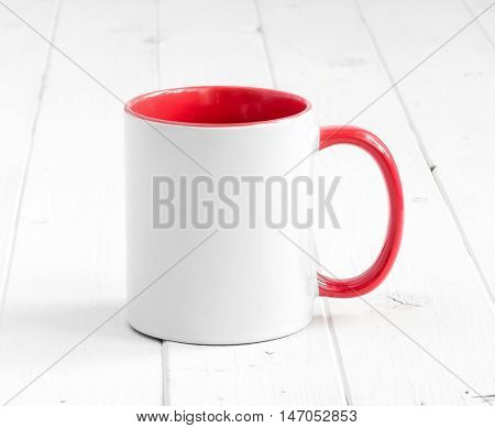 simple white cup with red inside and handle on a planked table