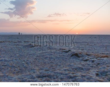 Sunrise in Sahara desert. Two man greeted dawn at salt lake. Egypt.