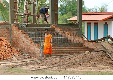 CHAMPASAK, LAOS - MAY 2015 : Young Buddhist novice holding a trowel at temple construction site in Champasak Province, southern Laos on May 24, 2015. 