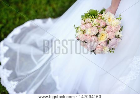Beautiful bride is holding a wedding colorful bouquet. Beauty of colored flowers. Close-up bunch of florets. Bridal accessories. Female decoration for girl. Details for marriage and for married couple