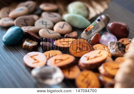 wooden, rune stone with his own hands among the crystals on a dark background